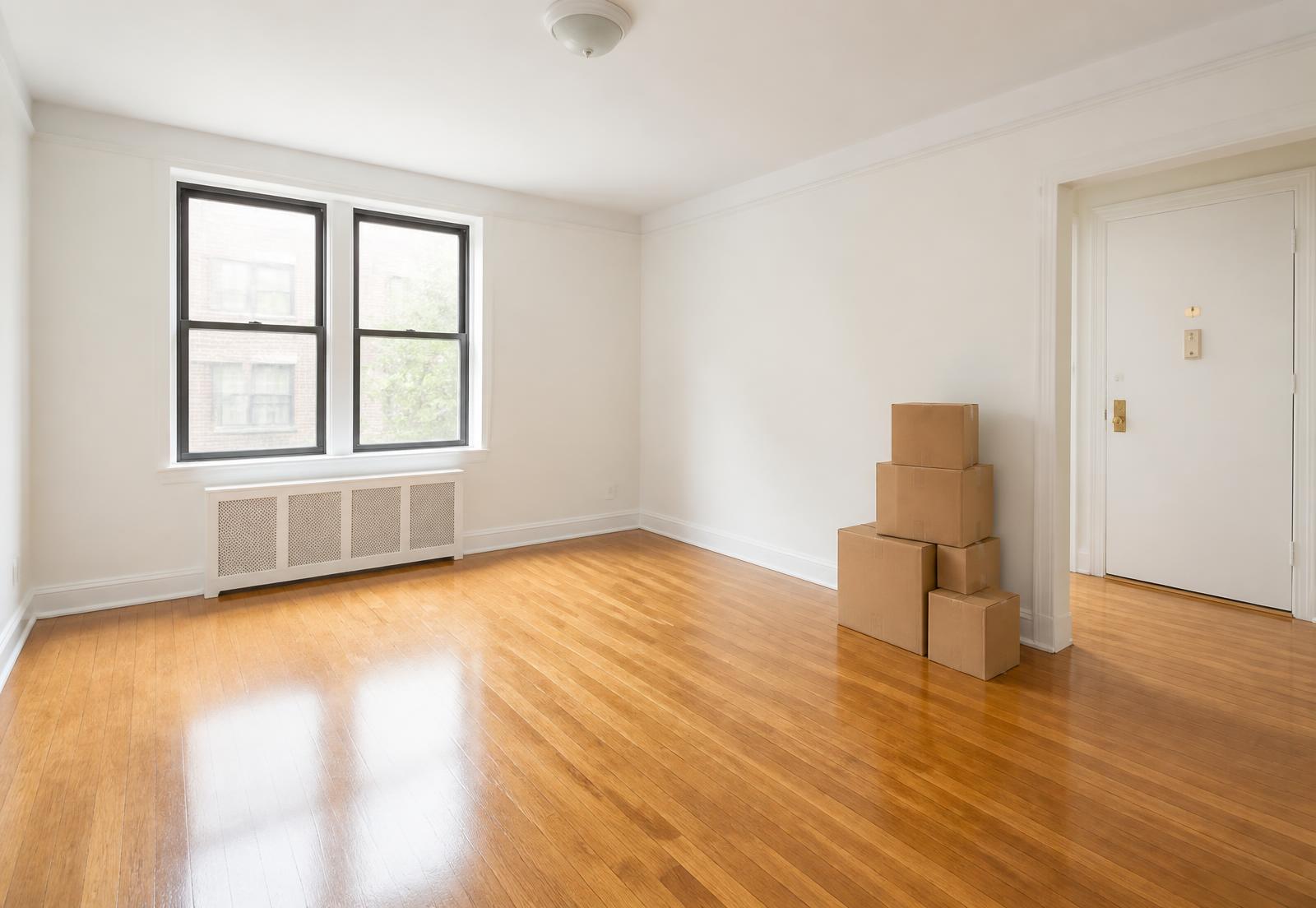 Empty apartment with clean bare floors and moving boxes by the door